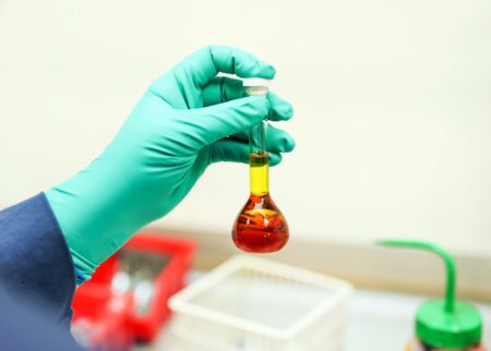 A hand holding a fuel sample in a laboratory