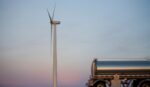 A fuel tanker passes by a wind turbine