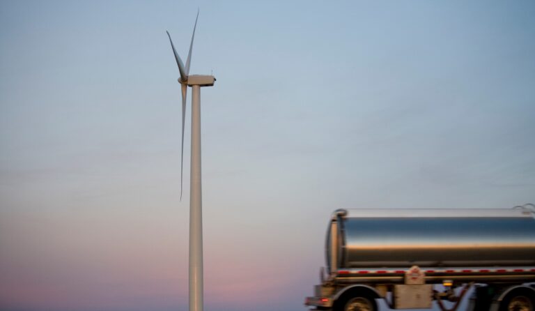 A fuel tanker passes by a wind turbine