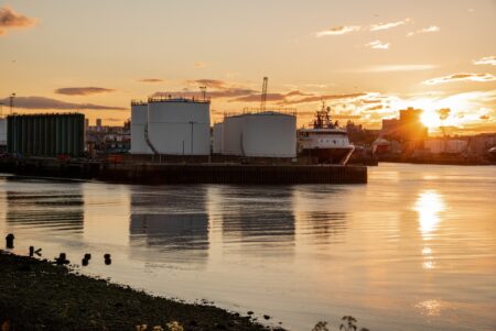 View of an industrial harbour at sunset. Oil tanks on a pier and docked ships in a commercial port at sunset. Aberdeen, Scotland, UK