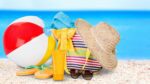 Beach ball, sun hat, flip flops and sunglasses on the beach