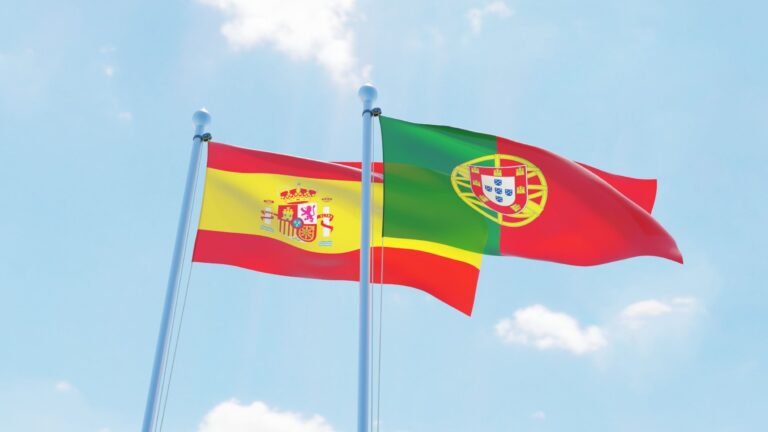 Spanish and portuguese flags on blue sky background